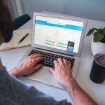 person using macbook pro on white table